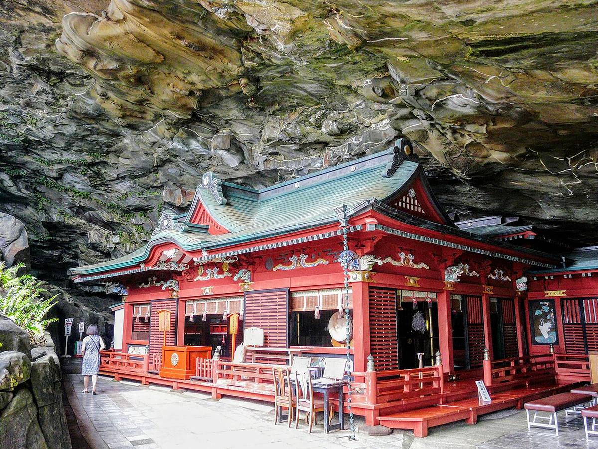 The vermilion main hall of Udo Jingu Shrine inside a seaside cave